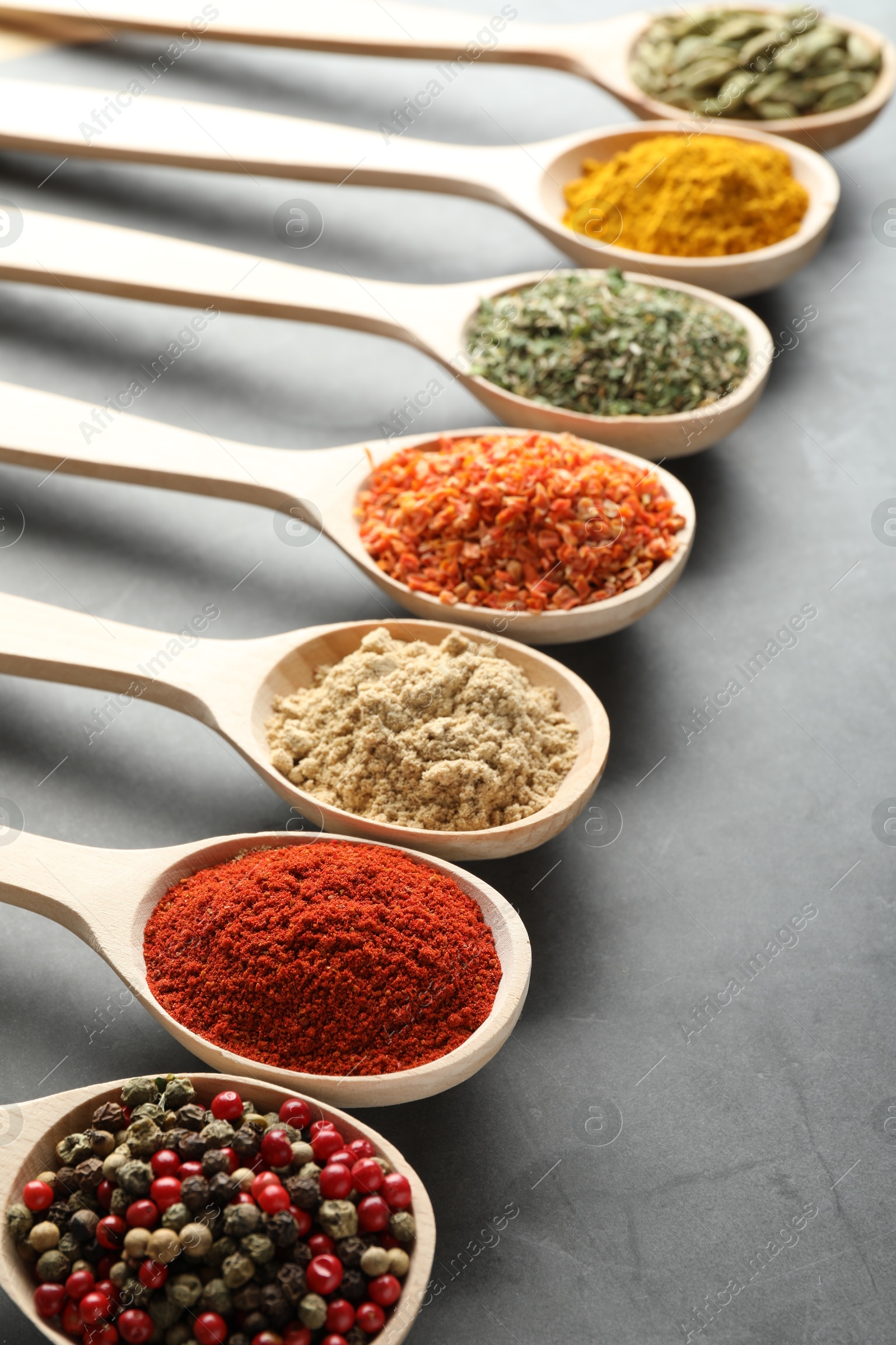 Many different spices in spoons on grey table, closeup Photo of Many different spices in spoons on grey table, closeup
