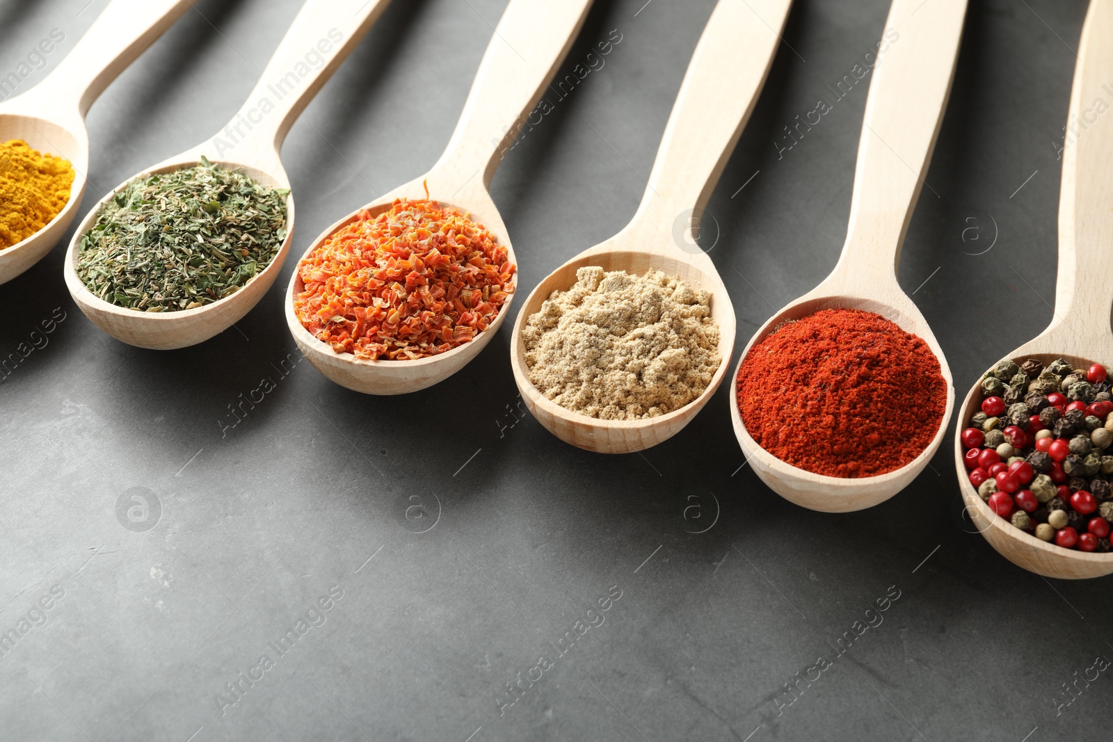 Many different spices in spoons on grey table, closeup Photo of Many different spices in spoons on grey table, closeup