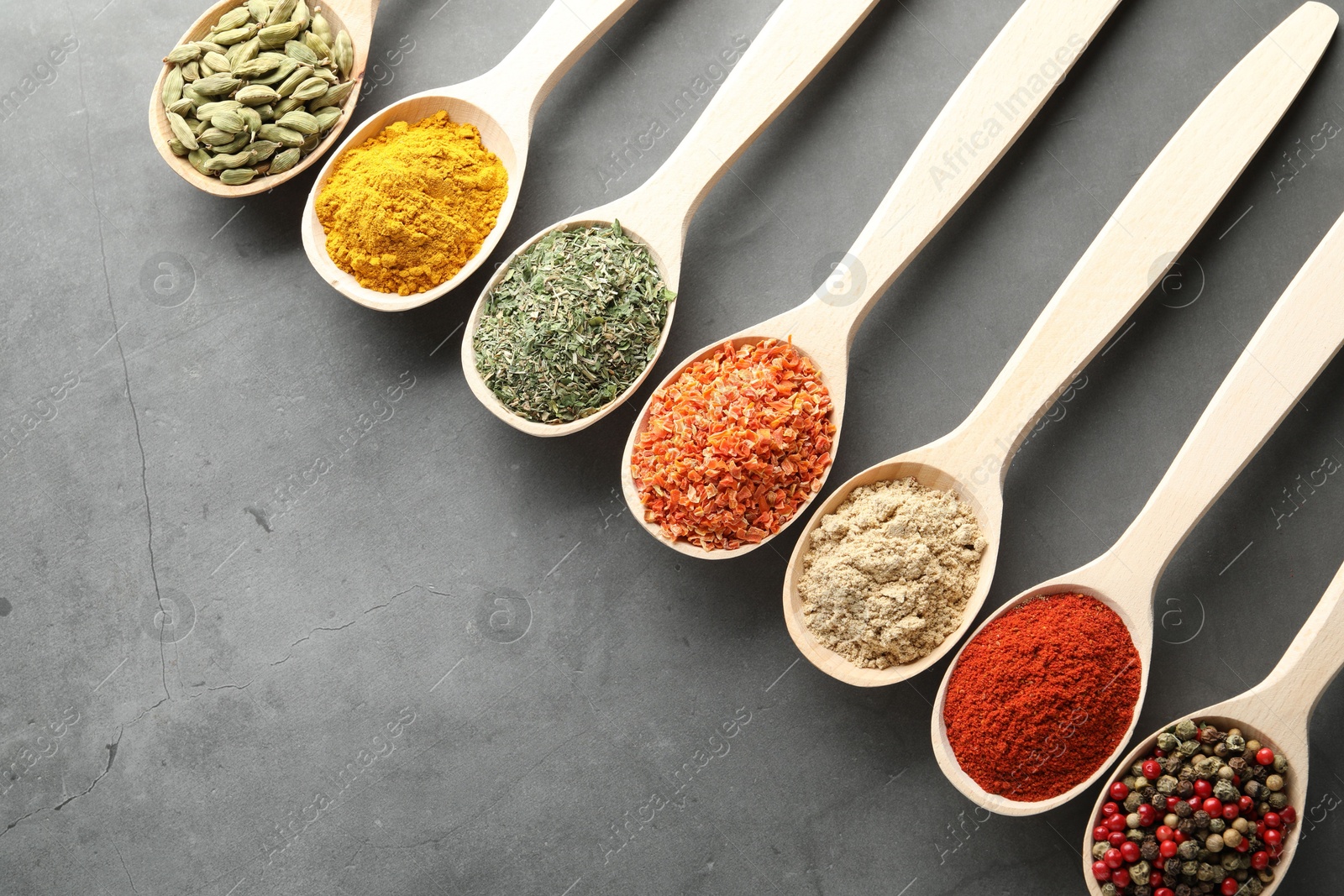 Many different spices in spoons on grey table, flat lay. Space for text Photo of Many different spices in spoons on grey table, flat lay. Space for text
