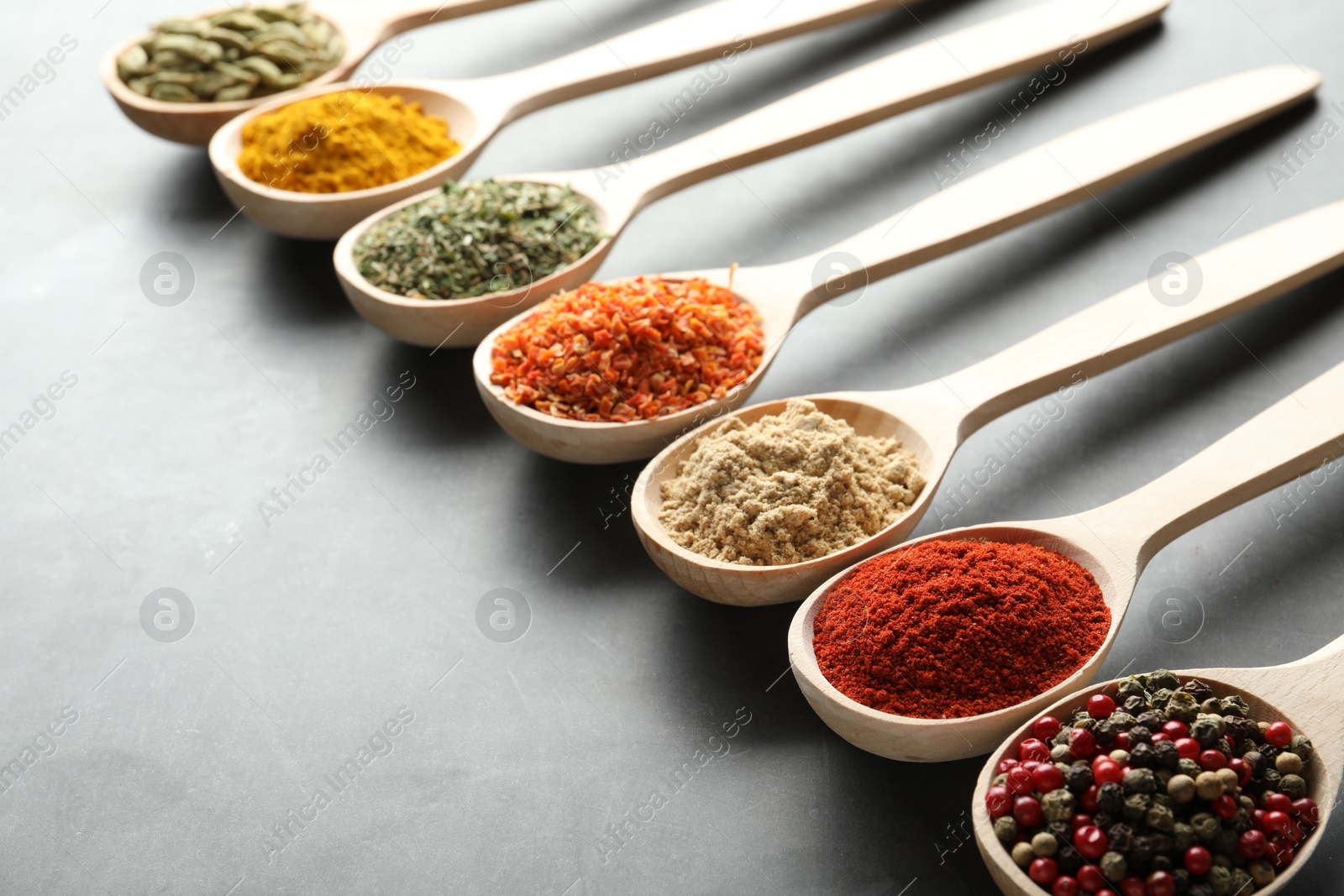 Many different spices in spoons on grey table, closeup Photo of Many different spices in spoons on grey table, closeup
