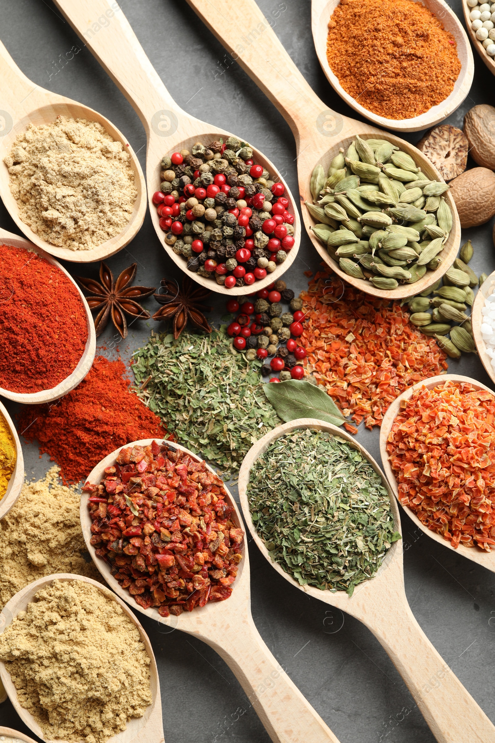 Many different spices in spoons on grey table, flat lay Photo of Many different spices in spoons on grey table, flat lay