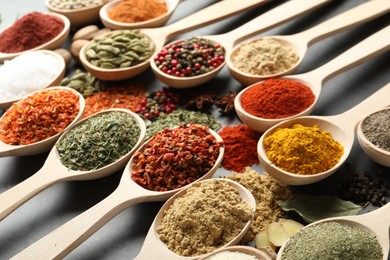 Photo of Many different spices in spoons on grey table, closeup