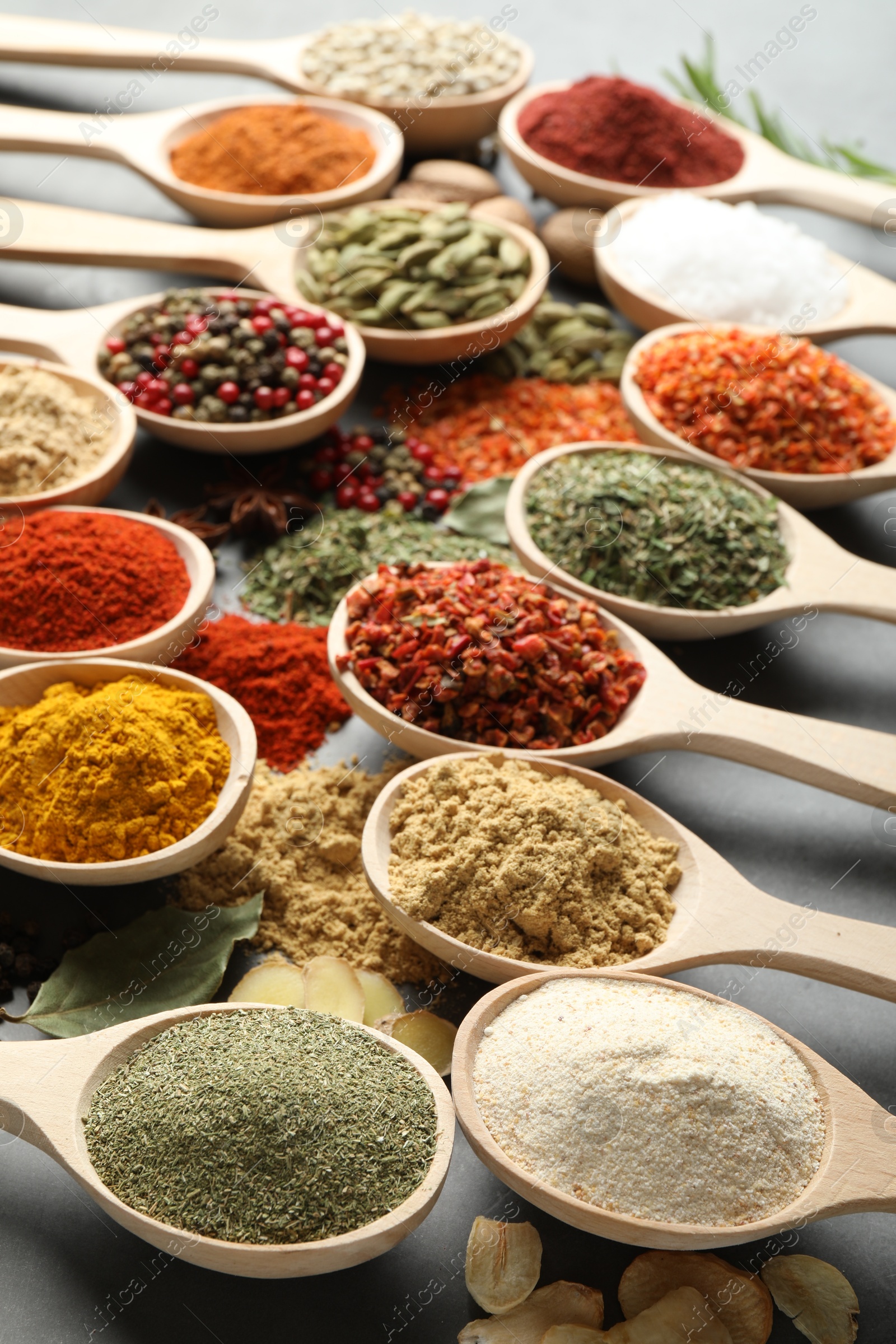 Many different spices in spoons on grey table, closeup Photo of Many different spices in spoons on grey table, closeup