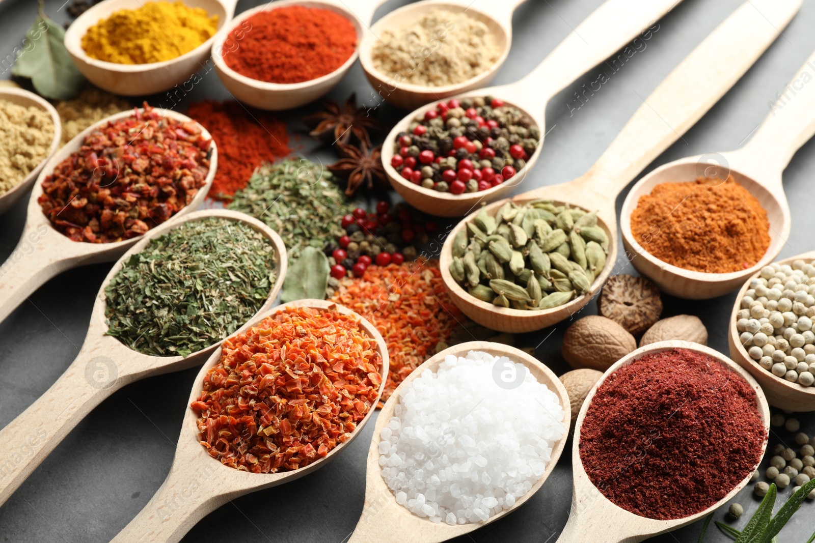 Many different spices in spoons on grey table, closeup Photo of Many different spices in spoons on grey table, closeup