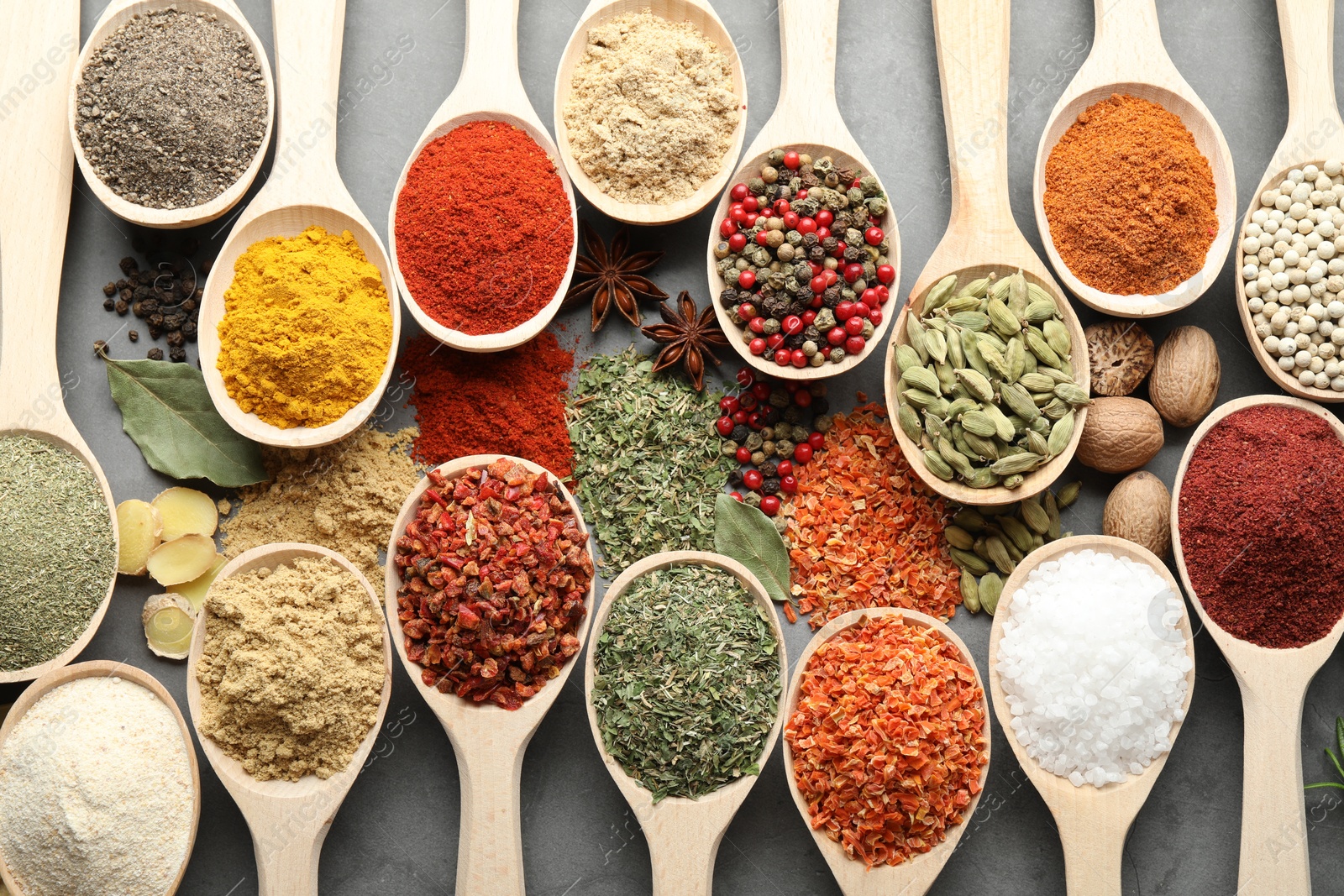 Many different spices in spoons on grey table, flat lay Photo of Many different spices in spoons on grey table, flat lay