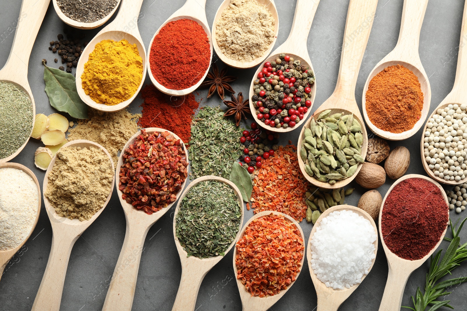 Many different spices in spoons on grey table, flat lay Photo of Many different spices in spoons on grey table, flat lay
