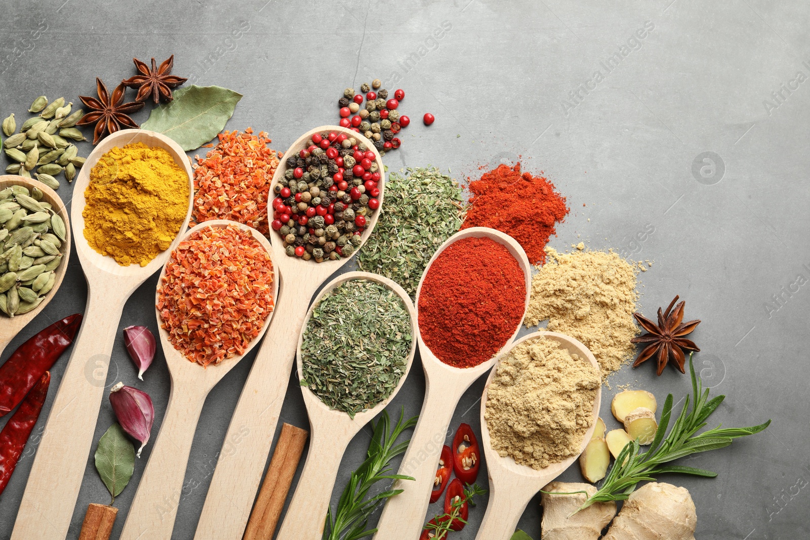 Many different spices in spoons on grey table, flat lay Photo of Many different spices in spoons on grey table, flat lay