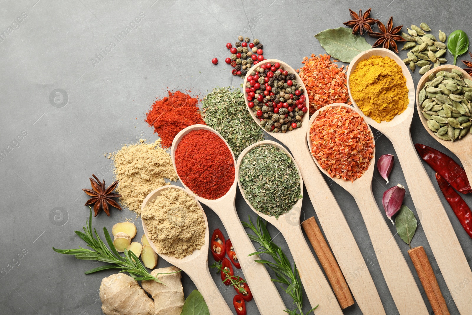 Many different spices in spoons on grey table, flat lay Photo of Many different spices in spoons on grey table, flat lay