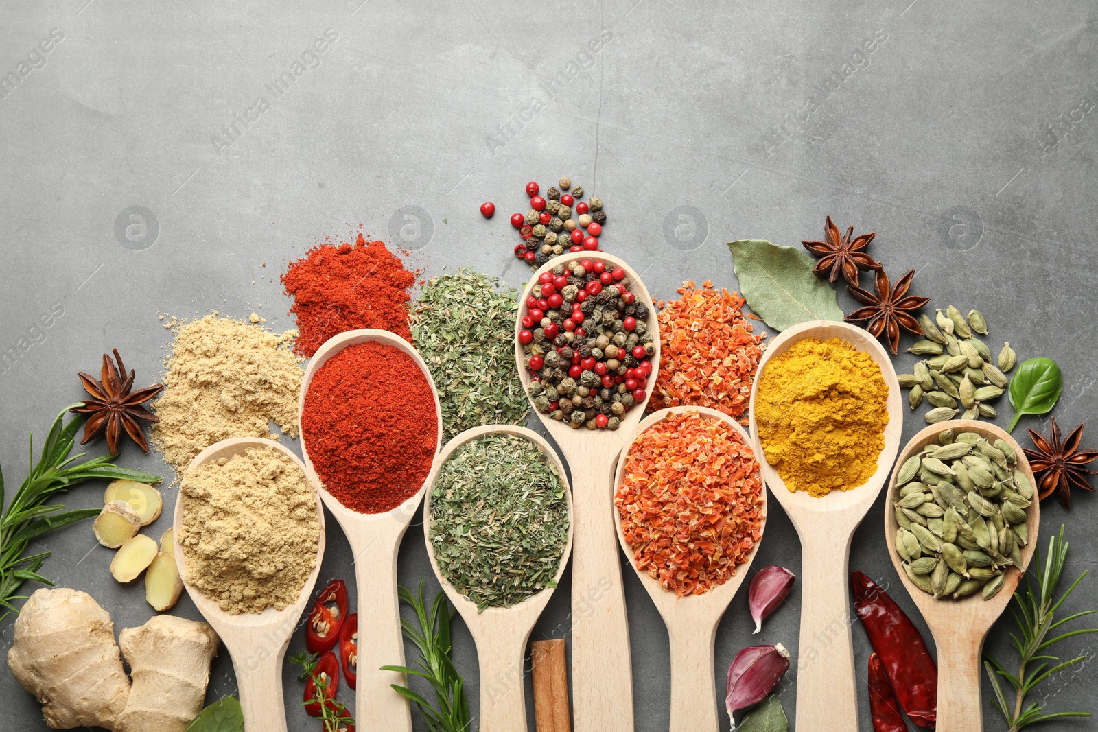 Many different spices in spoons on grey table, flat lay Photo of Many different spices in spoons on grey table, flat lay