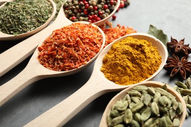 Photo of Many different spices in spoons on grey table, closeup