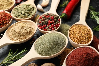 Photo of Many different spices in spoons on grey table, closeup