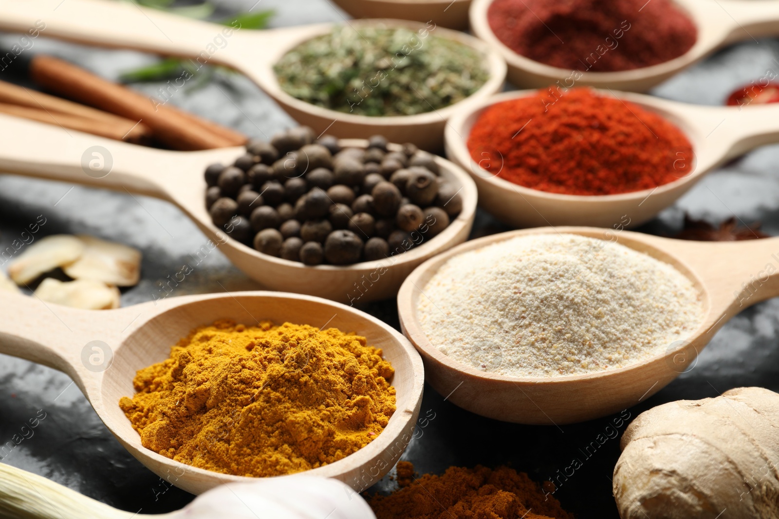Many different spices in spoons on black table, closeup Photo of Many different spices in spoons on black table, closeup