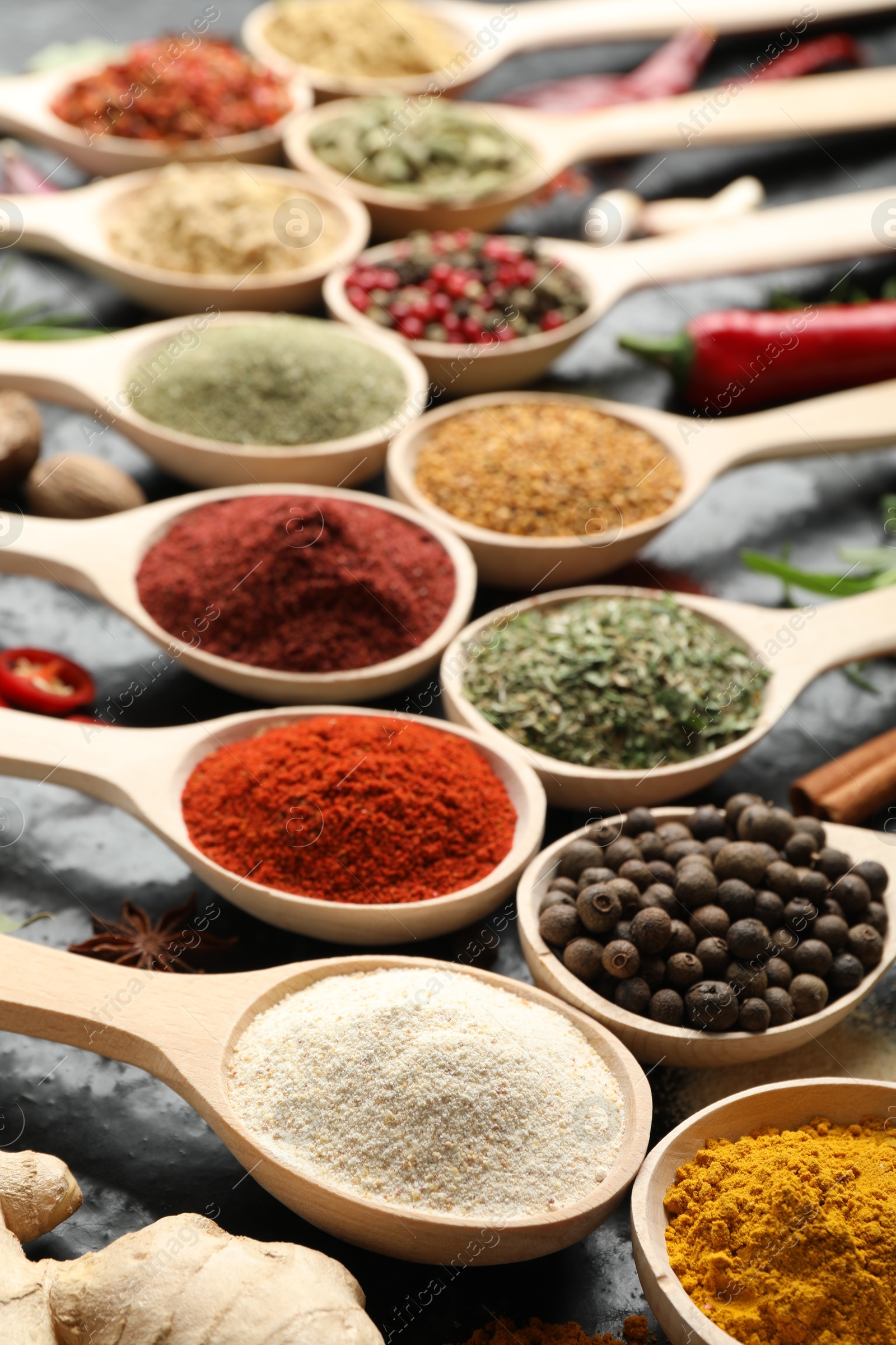 Many different spices in spoons on black table, closeup Photo of Many different spices in spoons on black table, closeup