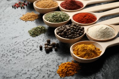 Photo of Many different spices in spoons on black table, closeup