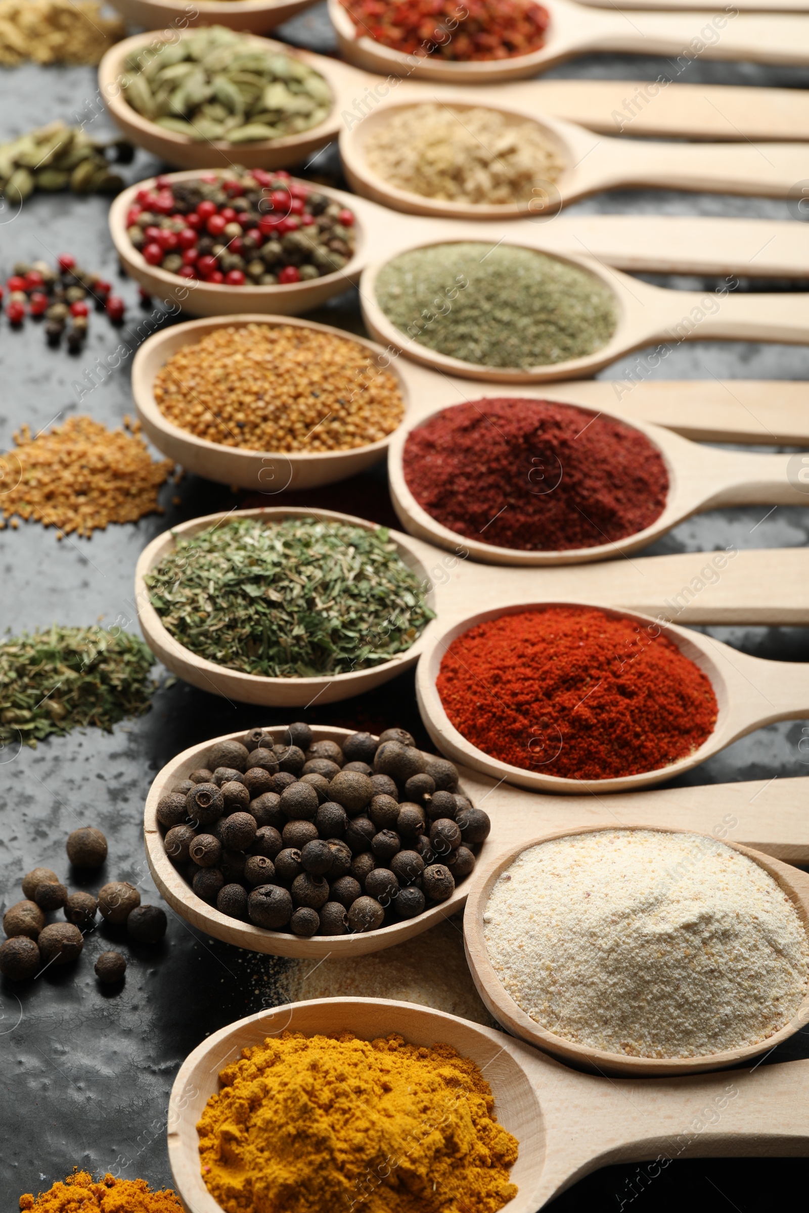 Many different spices in spoons on black table, closeup Photo of Many different spices in spoons on black table, closeup