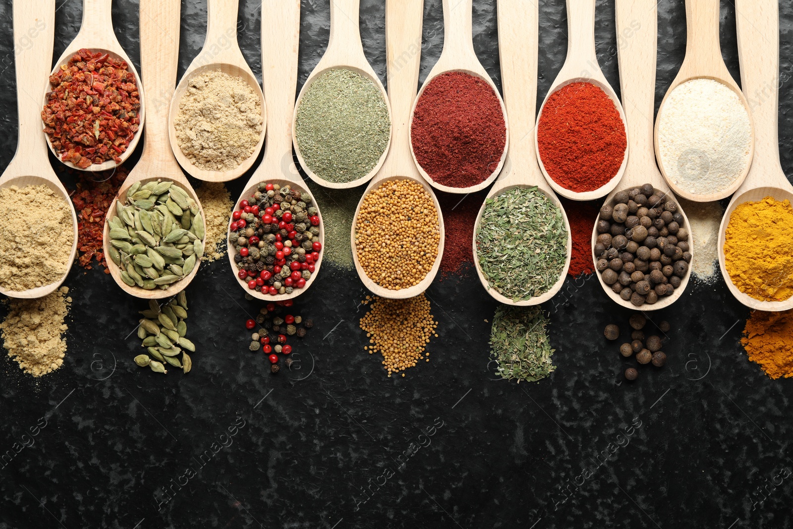 Many different spices in spoons on black table, flat lay Photo of Many different spices in spoons on black table, flat lay