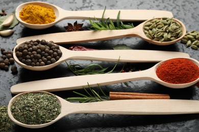 Photo of Many different spices in spoons on black table, closeup