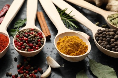 Photo of Many different spices in spoons on black table, closeup