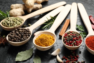 Photo of Many different spices in spoons on black table, closeup