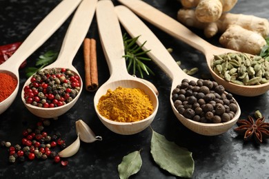 Photo of Many different spices in spoons on black table, closeup