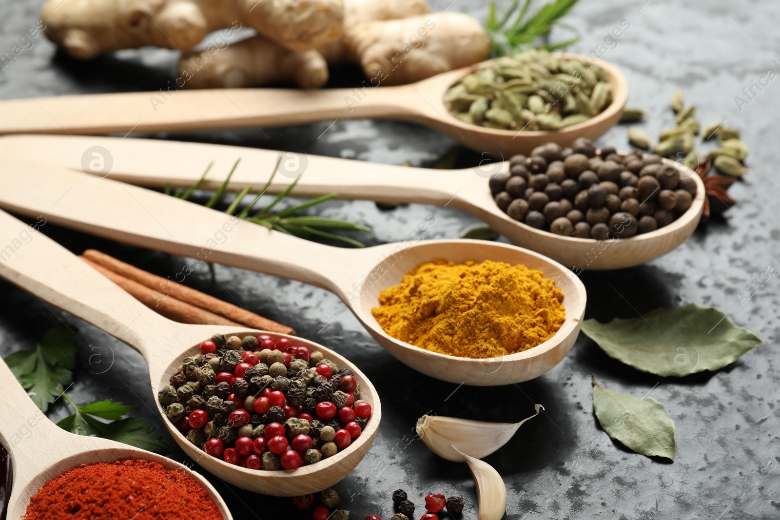 Many different spices in spoons on black table, closeup Photo of Many different spices in spoons on black table, closeup