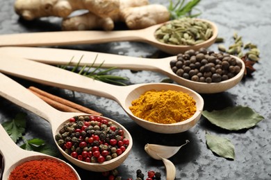Photo of Many different spices in spoons on black table, closeup