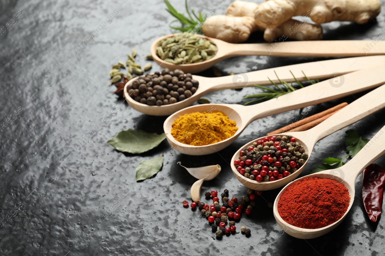 Many different spices in spoons on black table, closeup. Space for text Photo of Many different spices in spoons on black table, closeup. Space for text