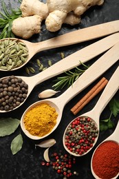 Photo of Many different spices in spoons on black table, flat lay