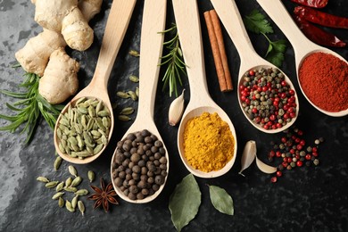 Photo of Many different spices in spoons on black table, flat lay