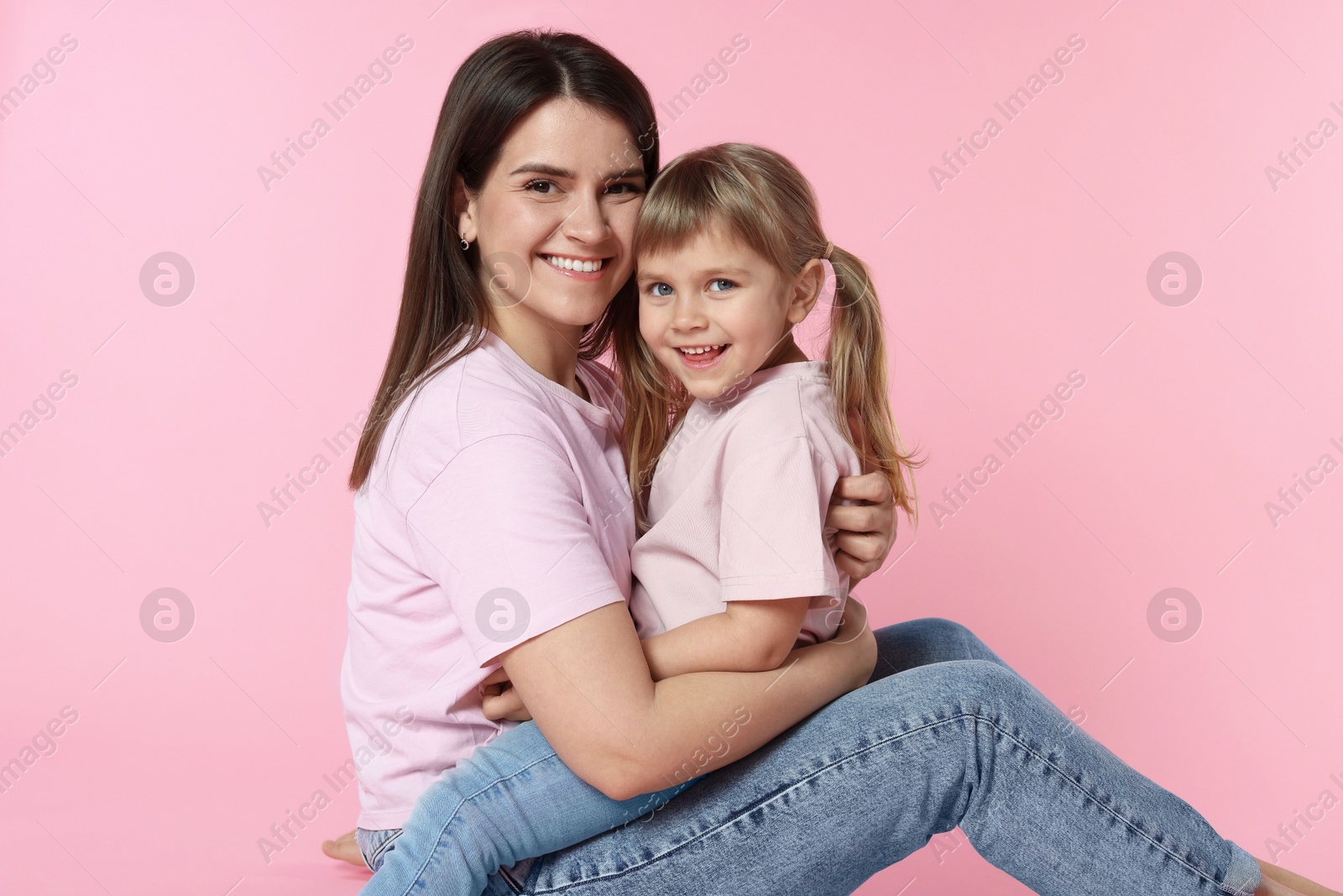 Happy mother and her cute daughter on pink background Photo of Happy mother and her cute daughter on pink background