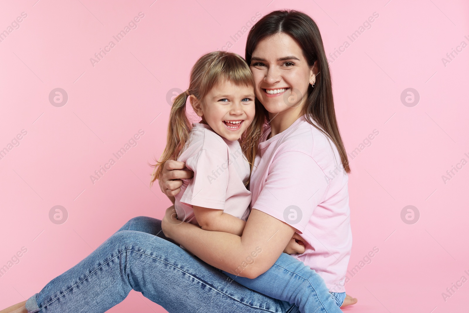 Happy mother and her cute daughter on pink background Photo of Happy mother and her cute daughter on pink background