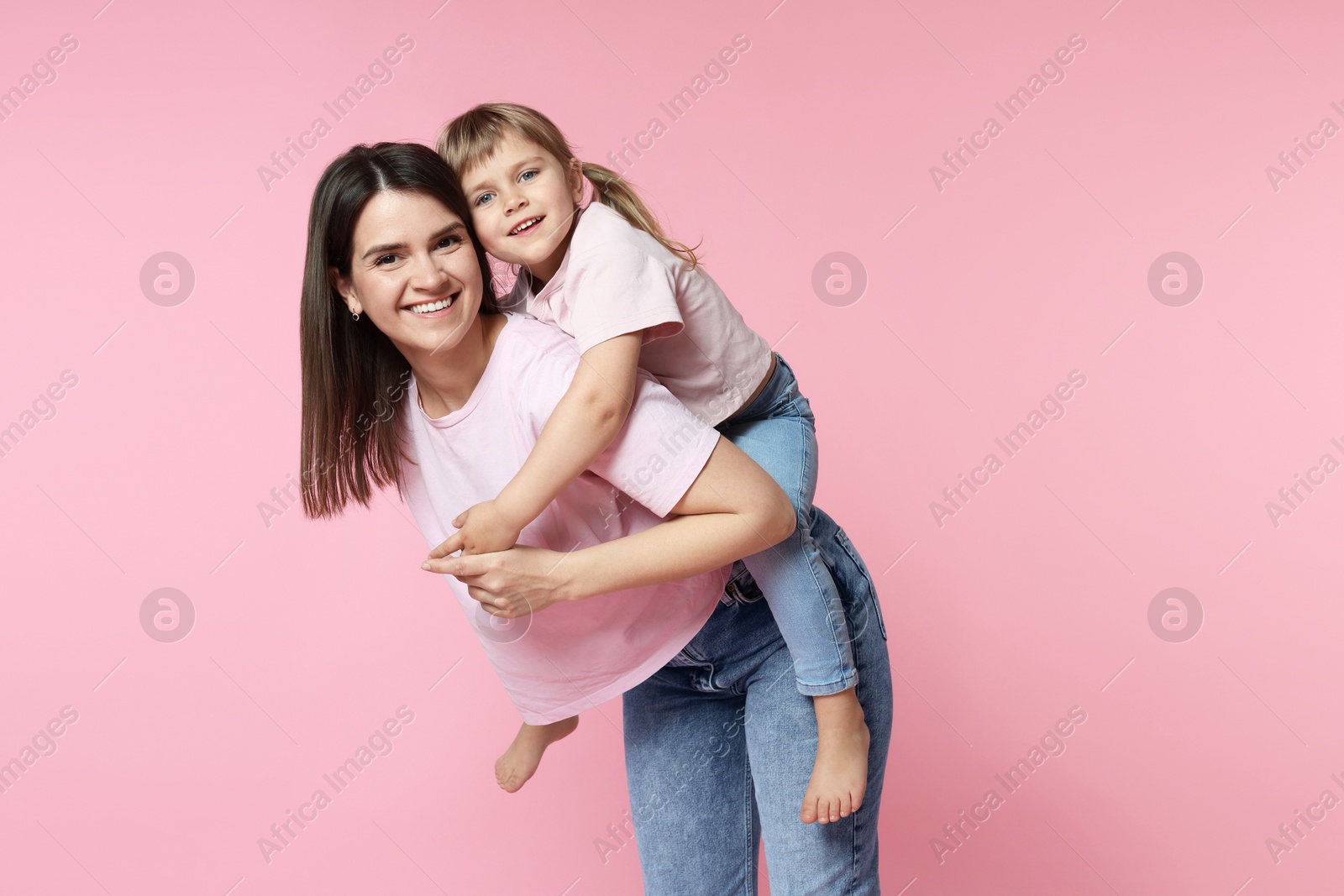 Happy mother and her cute daughter on pink background Photo of Happy mother and her cute daughter on pink background