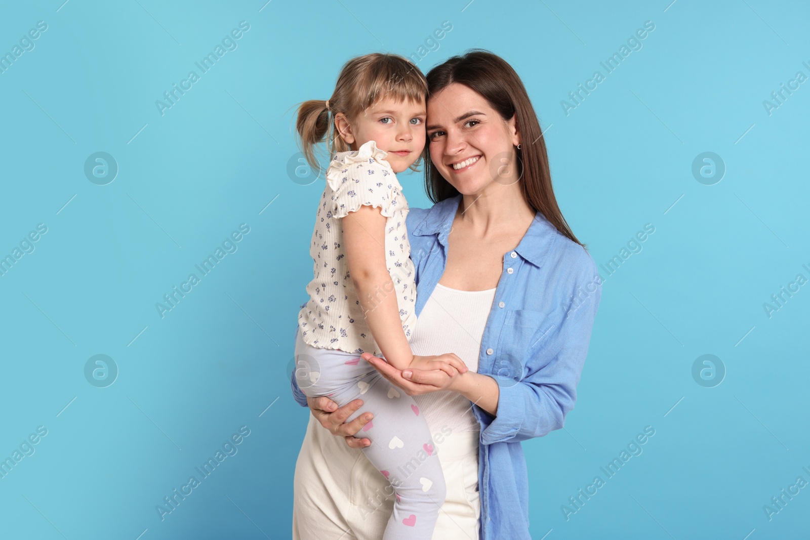 Photo of Happy mother and her cute daughter on light blue background