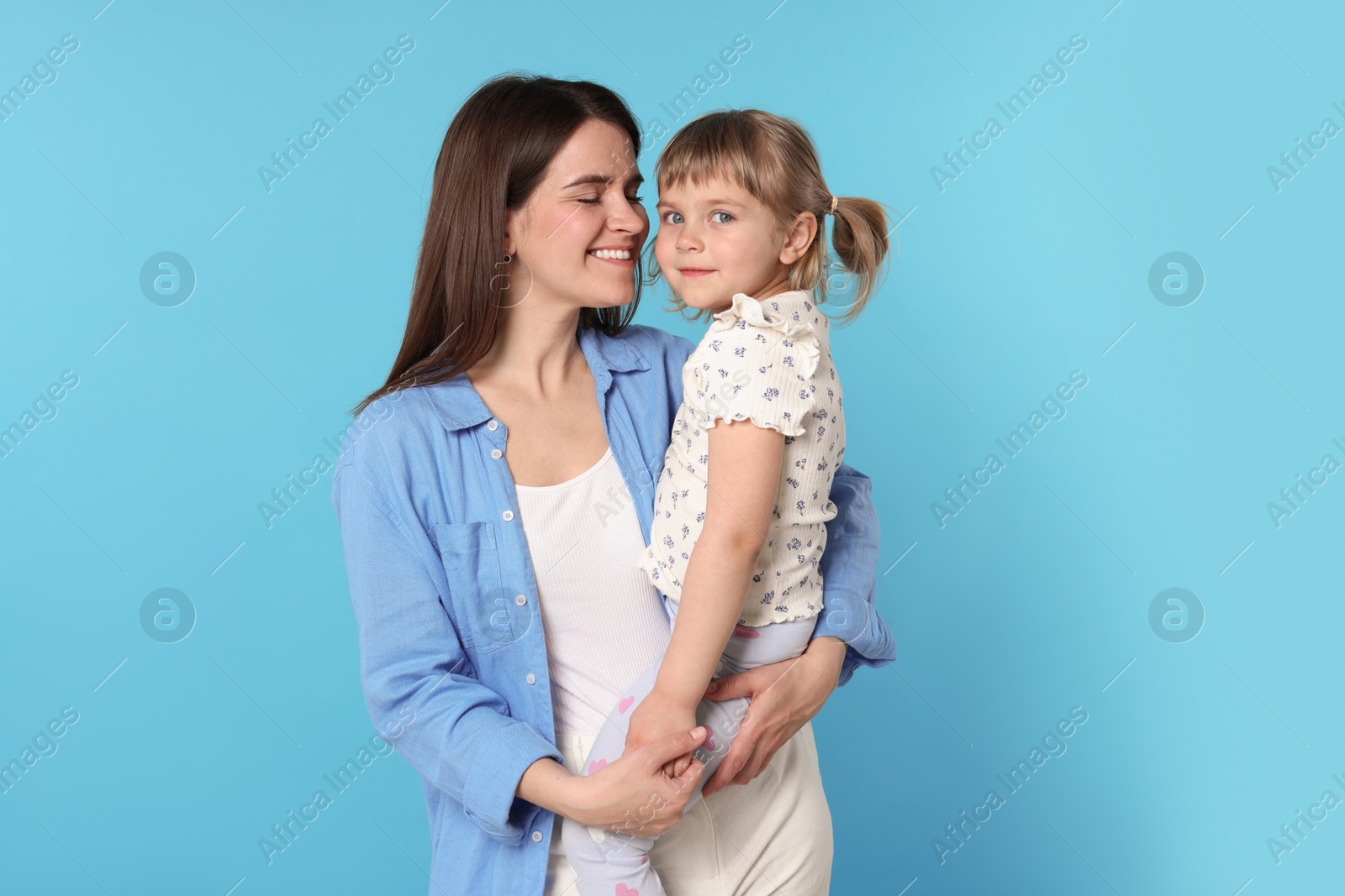 Photo of Happy mother and her cute daughter on light blue background