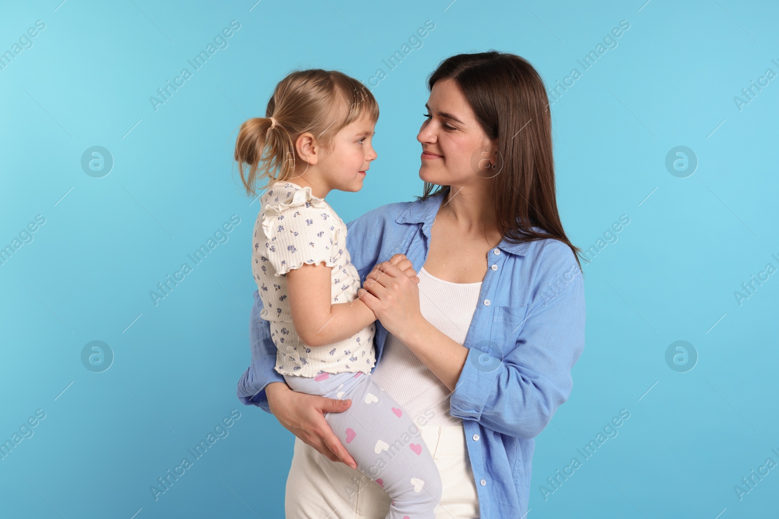 Photo of Happy mother and her cute daughter on light blue background