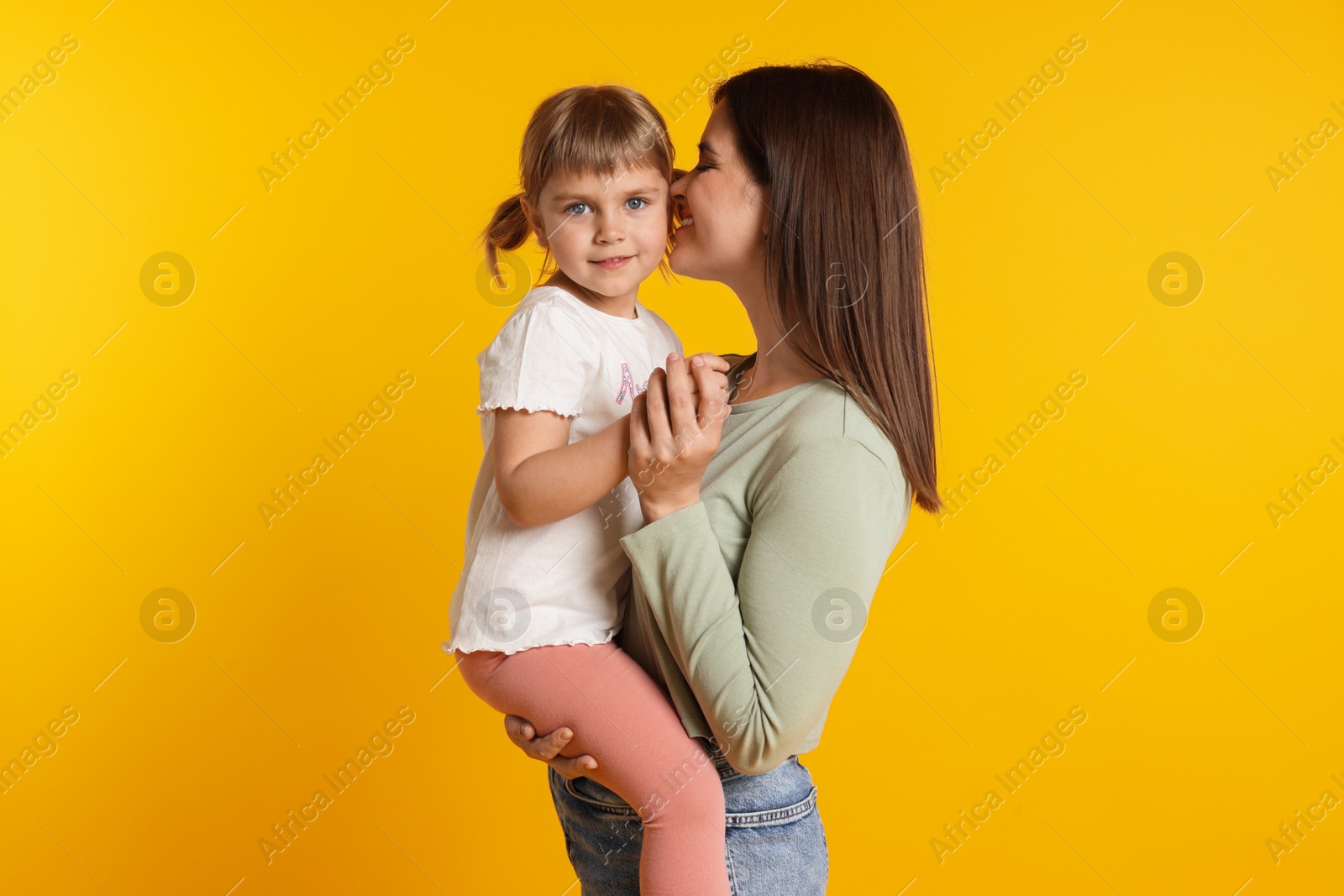 Happy mother and her cute daughter on orange background Photo of Happy mother and her cute daughter on orange background