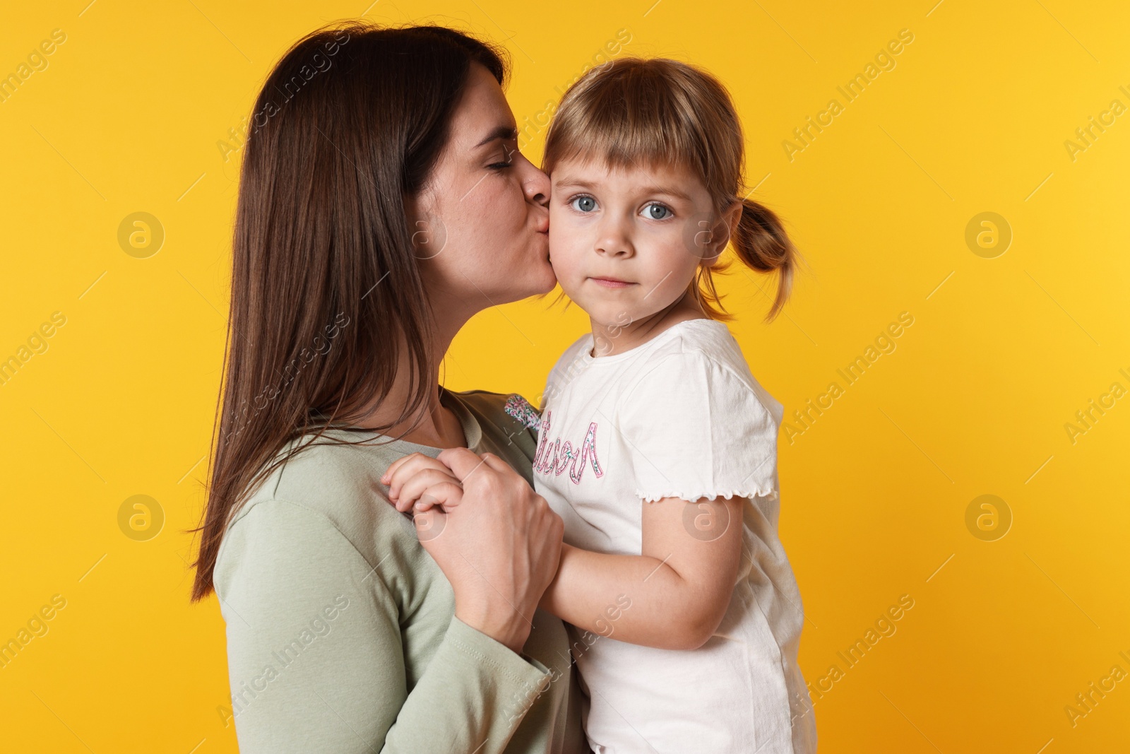 Happy mother and her cute daughter on orange background Photo of Happy mother and her cute daughter on orange background