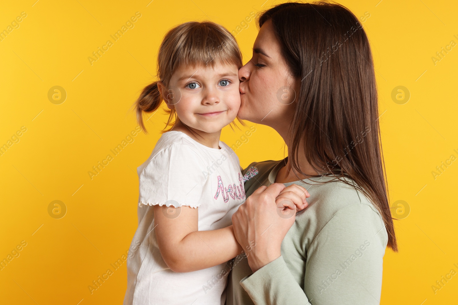Happy mother and her cute daughter on orange background Photo of Happy mother and her cute daughter on orange background