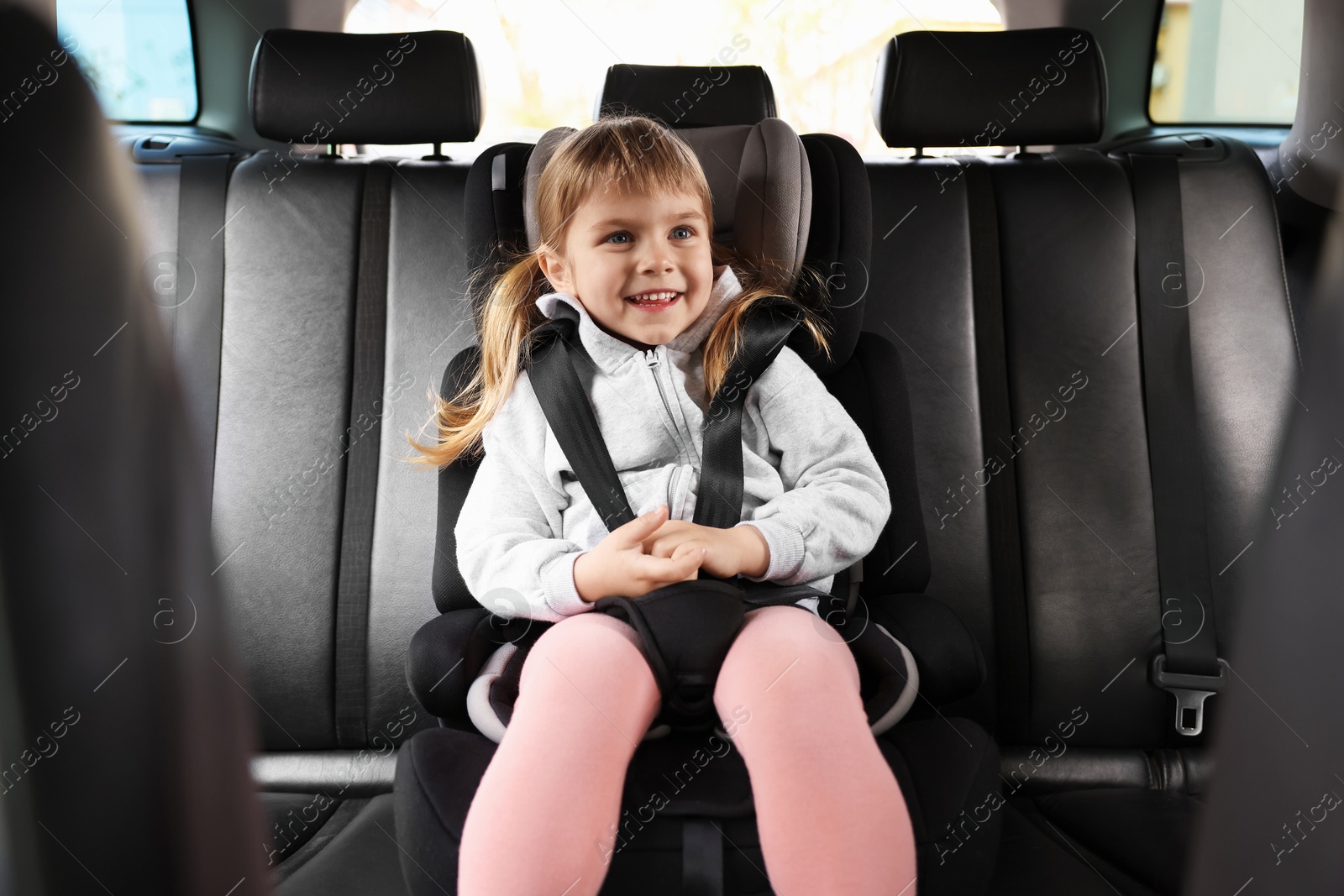 Photo of Little girl sitting in child safety seat inside car