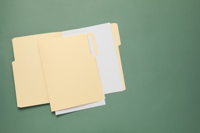 Photo of File folders with papers on green background, top view. Space for text