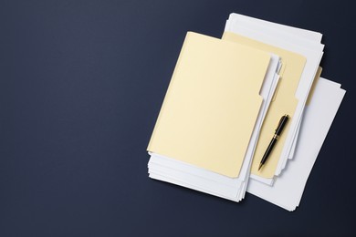 Photo of File folders with papers and pen on dark blue background, top view. Space for text