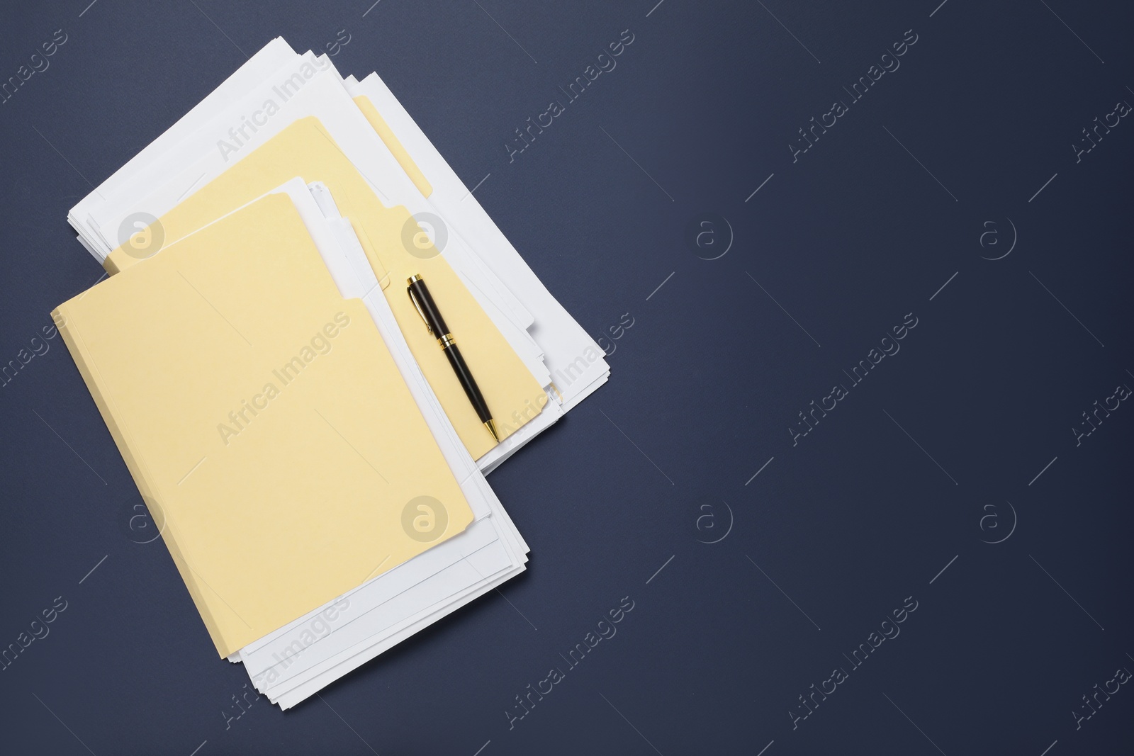 File folders with papers and pen on dark blue background, top view. Space for text Photo of File folders with papers and pen on dark blue background, top view. Space for text