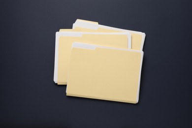 Photo of File folders with papers on dark background, top view