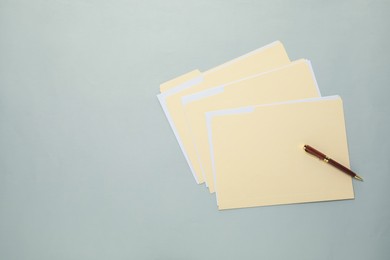 Photo of File folders with papers and pen on gray background, top view. Space for text