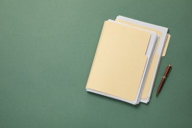 Photo of File folders with papers and pen on green background, flat lay. Space for text