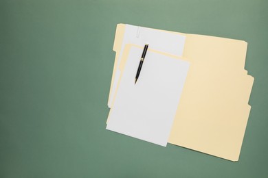 Photo of Paper file folders with blank sheets and pen on green background, top view. Space for text