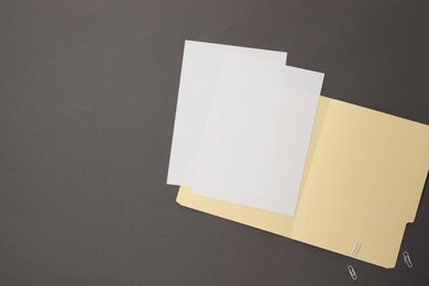 Photo of File folder with blank sheets and paper clips on gray background, flat lay. Space for text