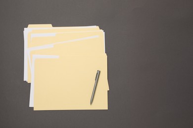 Photo of File folders with papers and pen on gray background, top view. Space for text