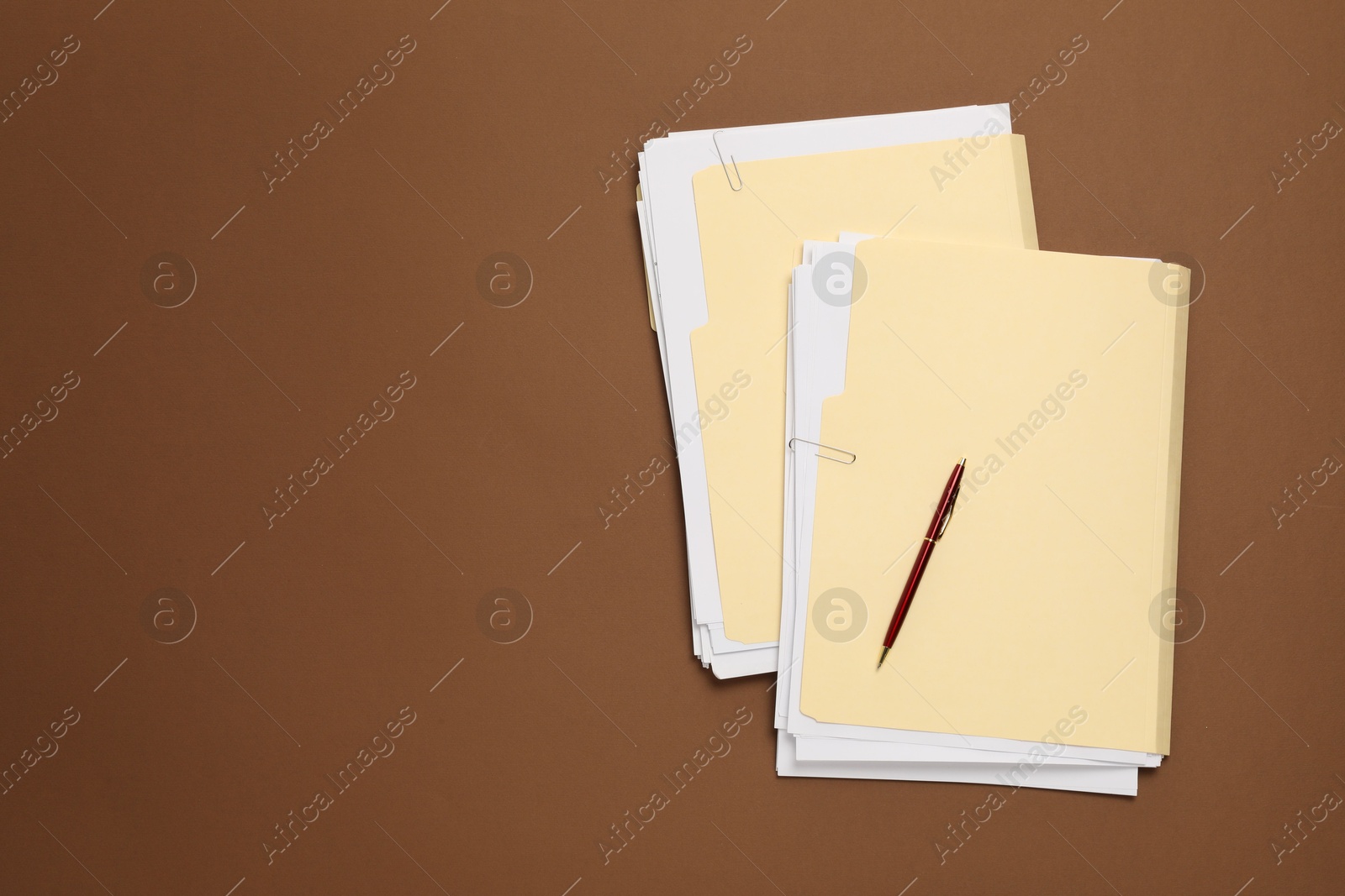 File folders with papers and pen on brown background, top view. Space for text Photo of File folders with papers and pen on brown background, top view. Space for text