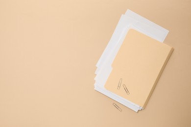Photo of File folder with sheets and paper clips on beige background, flat lay. Space for text